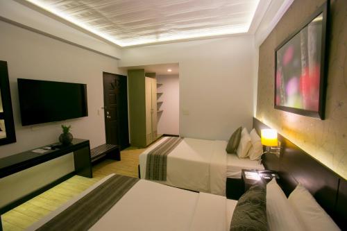 Venus Parkview Hotel في باغيو: غرفة فندقية بسرير وتلفزيون بشاشة مسطحة