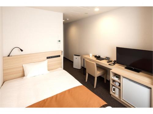 a bedroom with a desk and a bed and a television at Y's Hotel Asahikawa Ekimae in Asahikawa