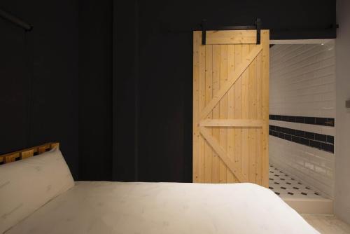 a bedroom with a bed and a wooden door at 被愛咖啡小旅館 Birdeye Garden in Tainan