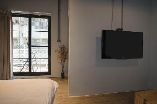 a room with a flat screen tv hanging on a wall at 被愛咖啡小旅館 Birdeye Garden in Tainan