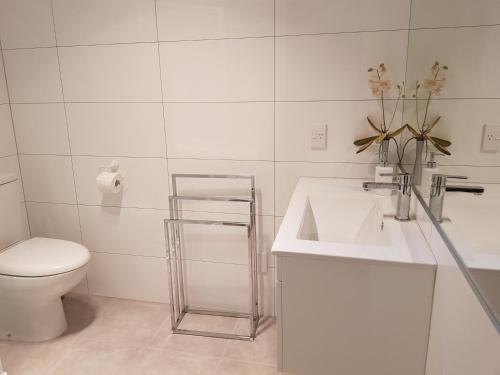 La salle de bains blanche est pourvue d'un lavabo et de toilettes. dans l'établissement Botanical Haven BnB, à Tauranga