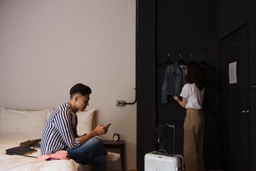 a man sitting on a bed looking at his cell phone at 被愛咖啡小旅館 Birdeye Garden in Tainan