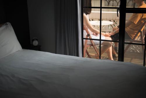 a woman sitting on a balcony with a bed at 被愛咖啡小旅館 Birdeye Garden in Tainan
