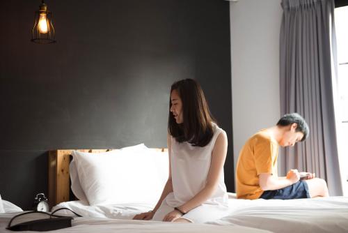 a man and a woman sitting on a bed at 被愛咖啡小旅館 Birdeye Garden in Tainan