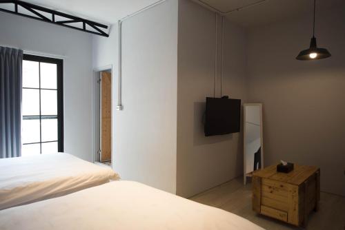a bedroom with a bed and a tv on the wall at 被愛咖啡小旅館 Birdeye Garden in Tainan