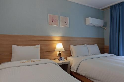 a hotel room with two beds and a table with a lamp at Benikea Swiss Rosen Hotel in Gyeongju