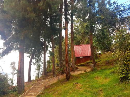 a cabin on a hill next to a body of water at Cabañas Yukatan Lago de Tota in Tota