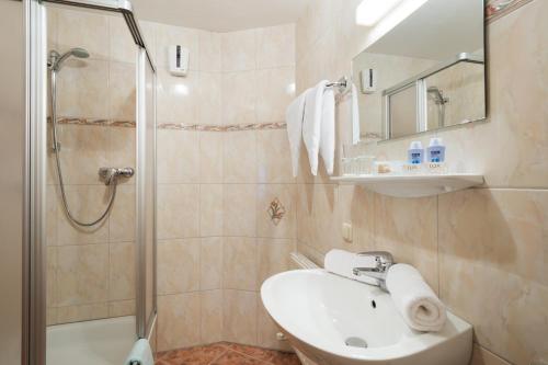 La salle de bains est pourvue d'un lavabo et d'une douche. dans l'établissement Altachhof Hotel und Ferienanlage, à Saalbach-Hinterglemm