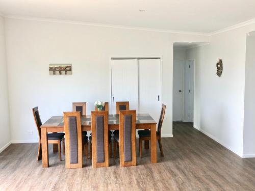 a dining room with a wooden table and chairs at Otaki Beachfront Getaway in Otaki Beach