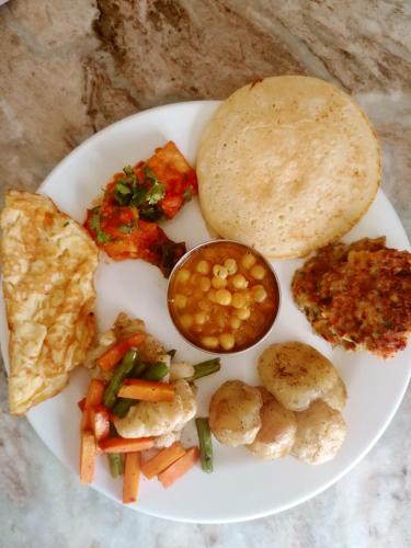 a white plate of food with a plate of food with bread at Aarya Chaitya Inn in Kathmandu