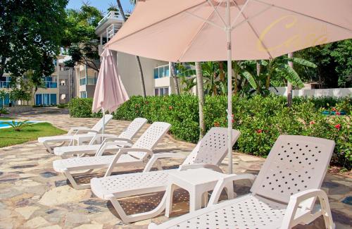 a row of white chairs and an umbrella at Tropical Casa Laguna in Cabarete