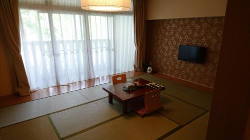 a living room with a small table and a television at Itoen Hotel Kusatsu in Kusatsu