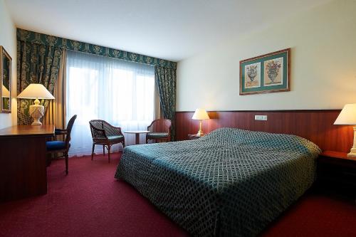 Cette chambre comprend un lit, un bureau et une fenêtre. dans l'établissement Hotel-Restaurant Ruyghe Venne, à Westerbork