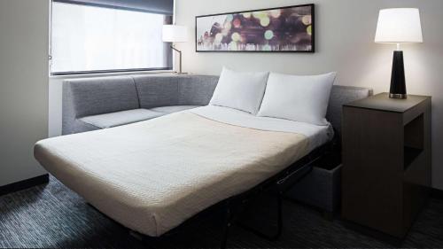 a bedroom with a bed and a chair and a window at Hyatt House Jersey City in Jersey City