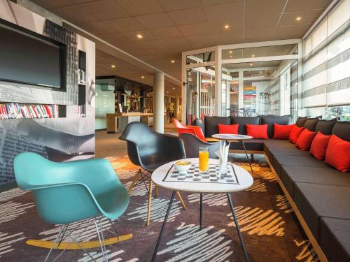 a lobby with chairs and a couch and a tv at ibis Deauville Centre in Deauville