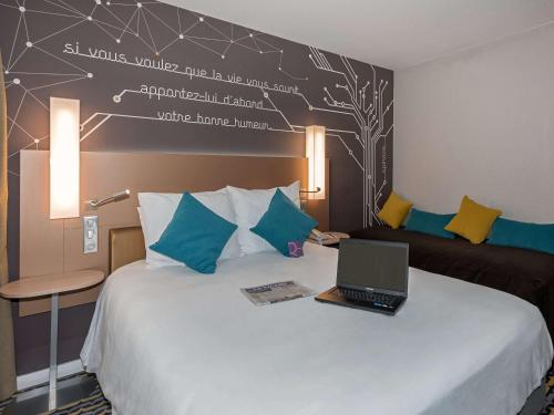 a hotel room with a bed with a laptop on it at Mercure Paris Sud Les Ulis-Courtaboeuf in Les Ulis