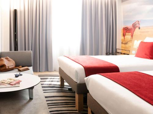 a hotel room with two beds and a table at Novotel Lyon Gerland Musée des Confluences in Lyon