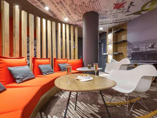 an orange couch in a restaurant with tables and chairs at ibis Marseille Timone in Marseille