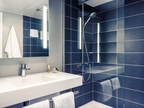 a blue tiled bathroom with a sink and a shower at Mercure Compiègne Sud in Compiègne