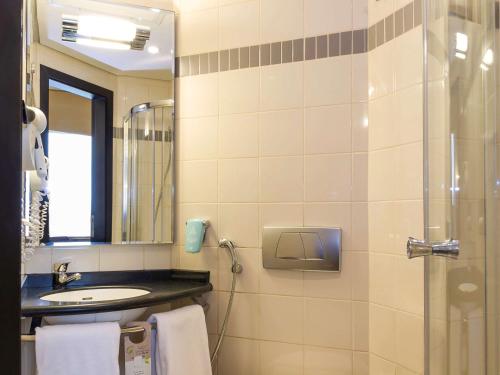 a bathroom with a sink and a shower with a mirror at ibis Sharq in Kuwait