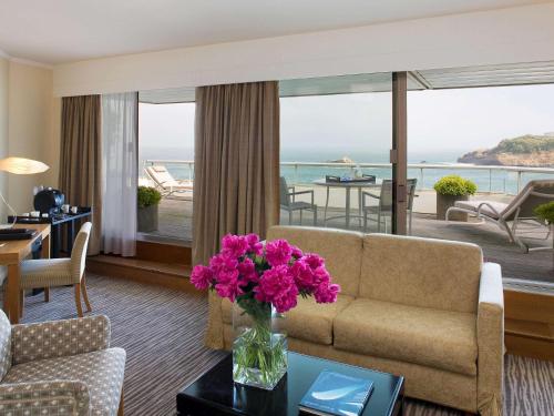 a living room filled with furniture and a balcony at Sofitel Biarritz Le Miramar Thalassa in Biarritz