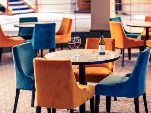 a table with two glasses of wine and chairs at Mercure Bolton Georgian House Hotel in Bolton