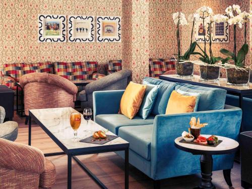 a living room with a blue couch and two tables at Mercure Maidstone Great Danes Hotel in Maidstone