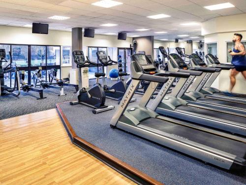 a woman walking through a gym with treadles at Mercure Maidstone Great Danes Hotel in Maidstone