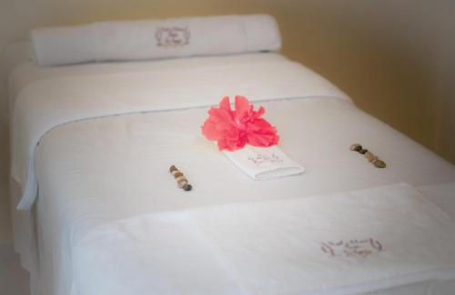 a white bed with a pink flower on it at Hotel y Cabañas Quinta Los Cipreses in Atlatlahucan