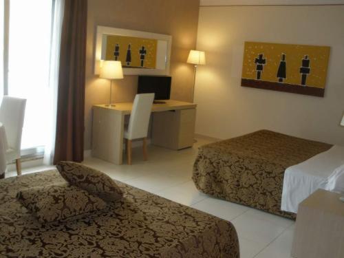 a hotel room with two beds and a desk at Mediterraneo Palace Hotel in Amantea