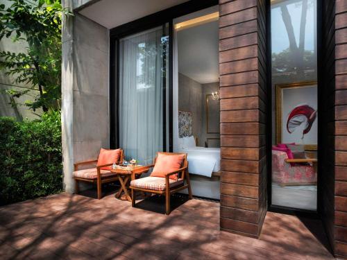 a patio with two chairs and a table and a bedroom at SO/ Sofitel Hua Hin in Cha Am