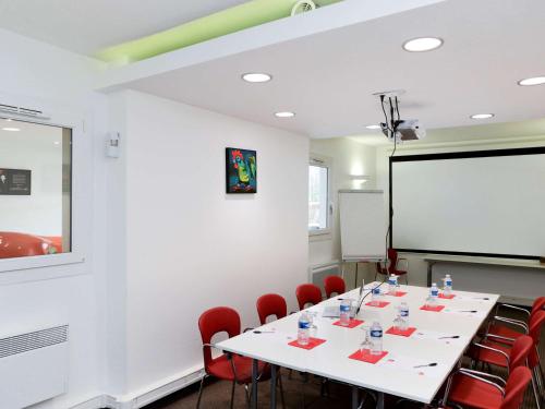 a conference room with a white table and red chairs at ibis Dole Sud Choisey in Dole