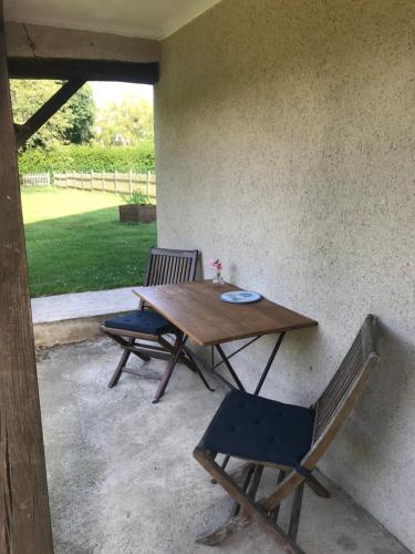 a table and two chairs sitting next to a wall at Le Poule House in Guérard