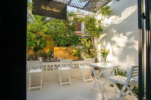 un patio con mesa, sillas y plantas en D Central Hoi An Homestay, en Hoi An