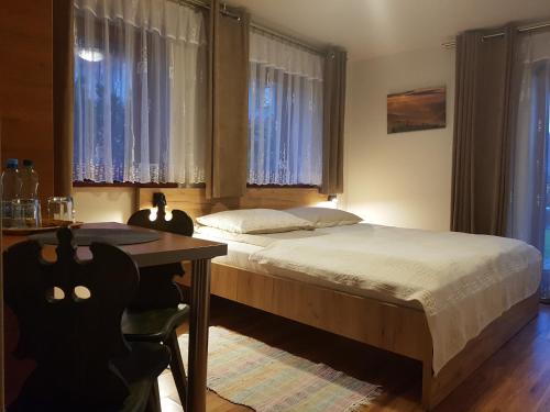 Schlafzimmer mit einem Bett, einem Tisch und Fenstern in der Unterkunft Pokoje Gościnne A.T. Mikołajczyk in Krościenko nad Dunajcem