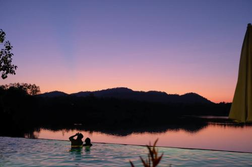 a group of people standing in the water at sunset at Inlaya Ratchaburi in Ratchaburi