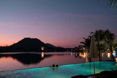 a pool with two people in the water at night at Inlaya Ratchaburi in Ratchaburi