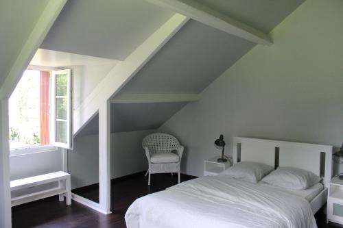 a bedroom with a white bed and a chair at Le Poule House in Guérard