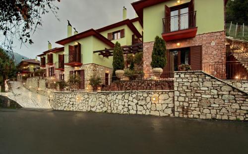 a large house with a stone retaining wall next to a street at Valtessiniko Studios in Valtessiniko