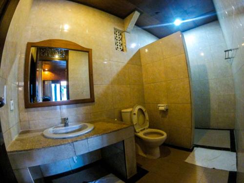 a bathroom with a toilet and a sink and a mirror at Leyeh Leyeh Homestay in Canggu