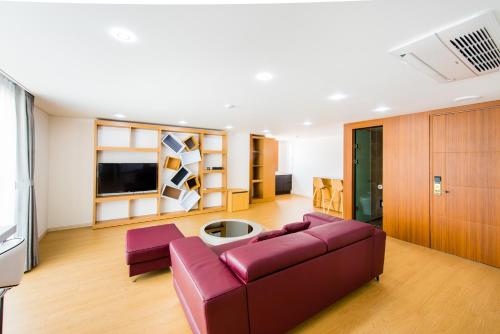 a living room with a purple couch and a tv at Fortuna Hotel in Tongyeong