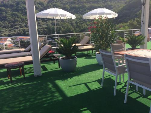 a balcony with chairs and tables and umbrellas at Guest house Villa Slavica in Sveti Stefan