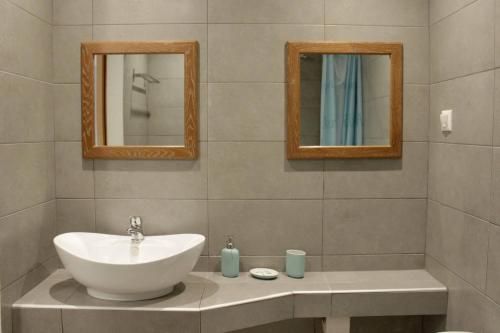 a bathroom with a white sink and two mirrors at Kehagias Apartments in Nea Vrasna