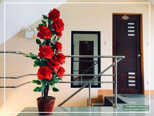 a vase with red flowers sitting on a glass floor at LCF - BB Hotel in Romblon