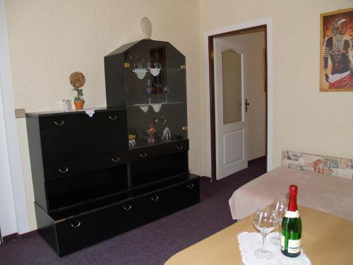 a room with a dresser and a table with a bottle of wine at Pension Erika in Františkovy Lázně