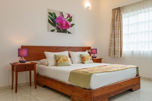 a bedroom with a bed with two tables and a window at Captain's Villa in Takamaka