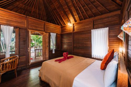 a bedroom with a bed with a red ribbon on it at Bunda 7 Bungalows in Nusa Lembongan