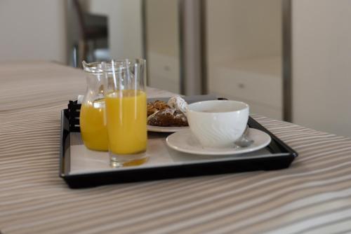 a tray with a plate of food and two glasses of orange juice at Best Western Hotel Principe di Lampedusa in Palermo