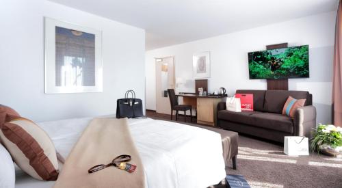 a hotel room with a bed and a living room at Centro Hotel U-NO1, Trademark Collection by Wyndham in Großbettlingen
