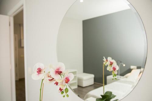 a mirror with flowers on a counter in a bathroom at Apartamentos Dacris in Jerte